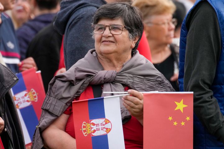 Μια γυναίκα κρατά σημαιάκια της Κίνας και της Σερβίας καθώς περιμένει την άφιξη του Κινέζου προέδρου Xi Jinping με τον Σέρβο ομόλογό του Aleksandar Vucic στο Σερβικό Παλάτι στο Βελιγράδι, Τετάρτη 8 Μαΐου 2024. (AP Photo/Darko Bandic)