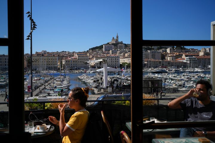 Ο κόσμος απολαμβάνει έναν καφέ σε ένα μπαλκόνι στο Παλιό Λιμάνι της Μασσαλίας στη νότια Γαλλία, Τρίτη 7 Μαΐου 2024. Η Ολυμπιακή δάδα θα μπει επιτέλους στη Γαλλία όταν φτάσει στο νότιο λιμάνι της Μασσαλίας την Τετάρτη. (AP Photo/Daniel Cole)