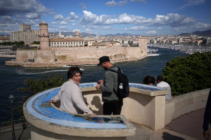 Οι άνθρωποι στέκονται στους κήπους του Palais du Pharo, με θέα στο παλιό λιμάνι, την ημέρα πριν από την άφιξη της Ολυμπιακής φλόγας, στη Μασσαλία, στη νότια Γαλλία, Τρίτη 7 Μαΐου 2024. (AP Photo/Laurent Cipriani)