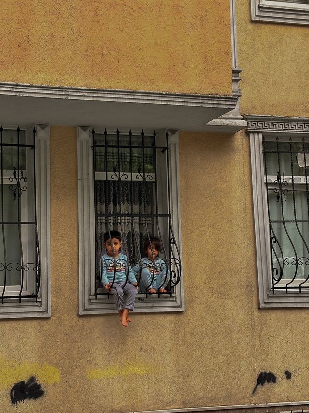 Παιδάκια πίσω από τα κάγκελα του σπιτιού τους χαζεύουν τους περαστικούς