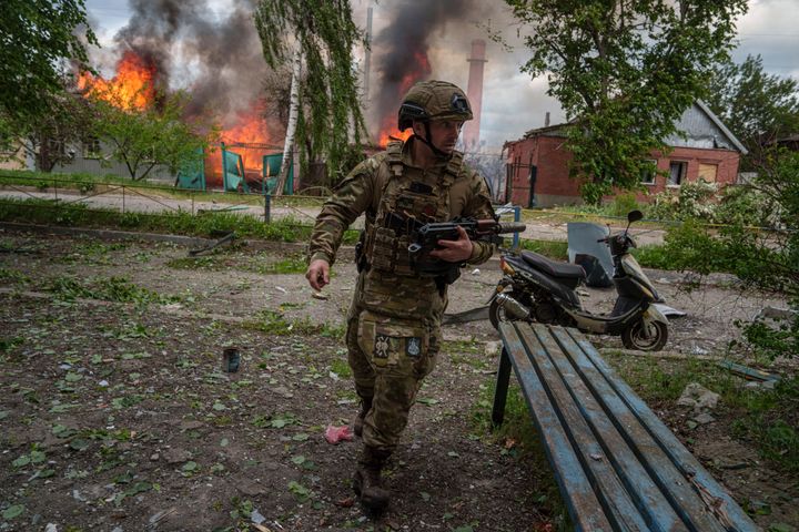 A police officer runs in front on burning house destroyed by a Russian airstrike in Vovchansk, Ukraine, on Saturday, May 11, 2024. (AP Photo/Evgeniy Maloletka)