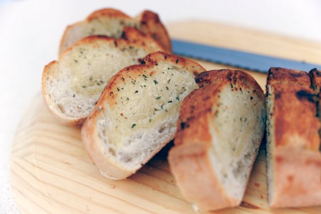 Crusty loaf of sour dough garlic bread on a wooden board with a knife
