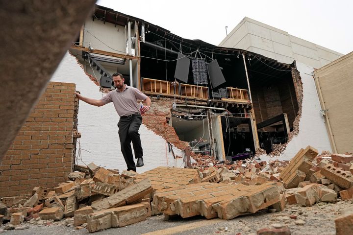 Ein Mann geht nach einem schweren Gewitter am Freitag, 17. Mai 2024, in Houston über heruntergefallene Ziegelsteine ​​eines beschädigten Gebäudes.  (AP Photo/David J. Phillip)