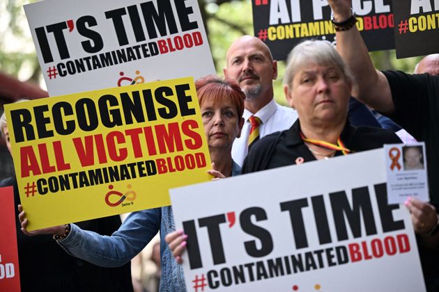 Demonstrators hold placards reading message related to the NHS infected blood scandal as Rishi Sunak is questioned by the Infected Blood Inquiry last year.