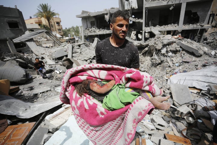 (EDITORS NOTE: Image depicts death) A Palestinian man carries the lifeless body of a child who was killed in an Israeli attack on the Nuseirat camp after she was pulled out of the rubble in Deir al-Balah, Gaza on May 19, 2024.