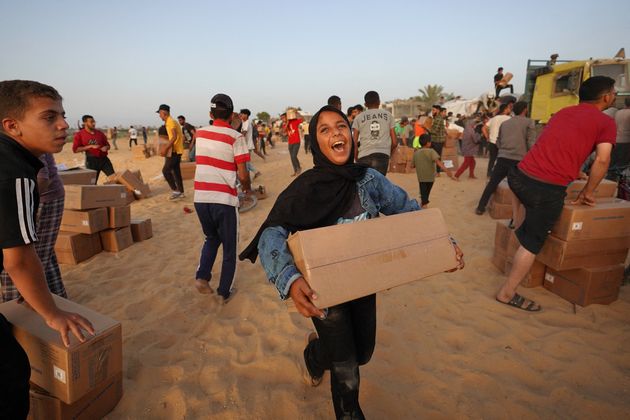 Palestinians carry boxes of humanitarian assistance after rushing the trucks transporting the international aid from the new U.S.-built temporary floating pier near Nuseirat in the central Gaza Strip on Saturday.