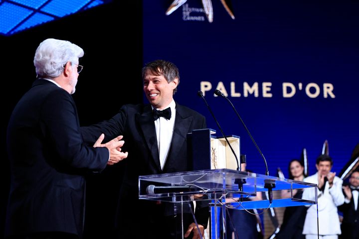 Director Sean Baker, right, smiles next to director George Lucas after winning the Palme d'Or for the film "Anora" during the Closing Ceremony at the 77th edition of the Cannes Film Festival in Cannes, southern France, on May 25, 2024. (Photo by VALERY HACHE/AFP via Getty Images)