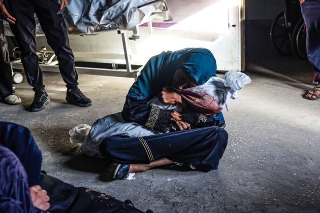 A Palestinian woman at a health clinic holds the shrouded body of a child killed in Israel's attack on a tent camp in Rafah's Tel al-Sultan neighborhood on May 26, 2024.