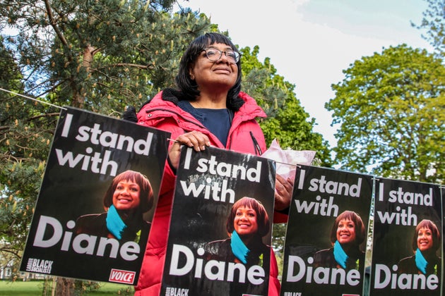Diane Abbot in Hackney Downs Park posing for photographs with campaign posters bearing the slogan 