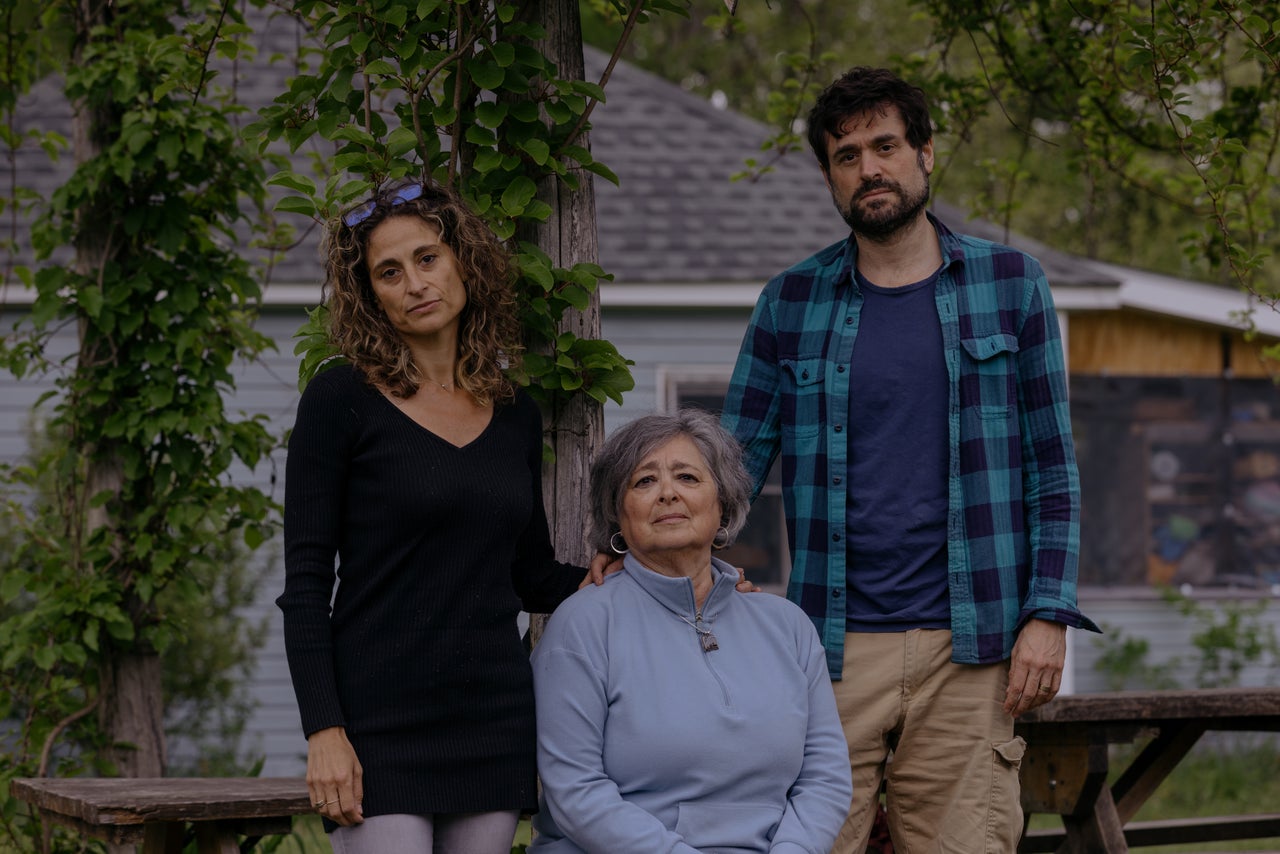 Andy's mother, Lainie Neiman (center), and his brother, David Neiman, pose with Emily outside her home.