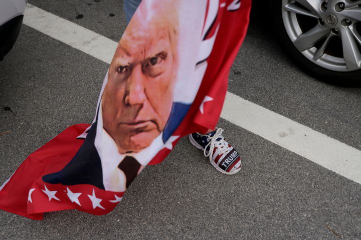 A flag featuring a portrait of Donald Trump is carried Thursday amid a group of Trump supporters near Mar-a-Lago in Palm Beach, Florida.