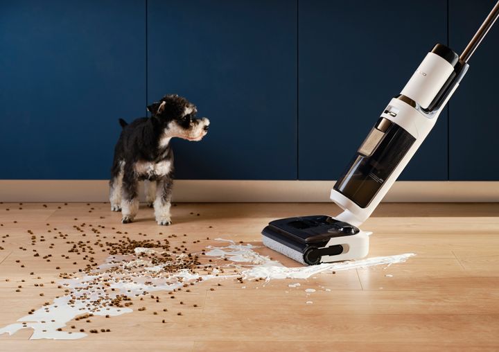The Tineco vacuum cleaning up spilled cereal in front of a cute dog