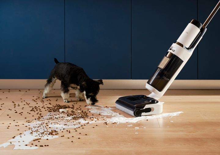The Tineco vacuum cleaning up spilled cereal in front of a cute dog