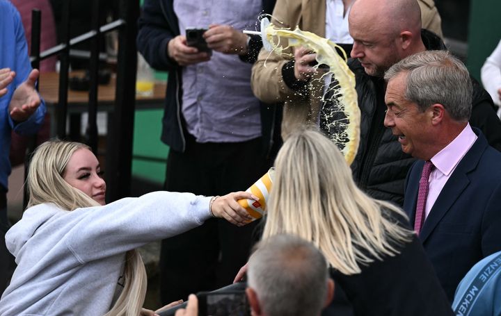 A woman throws a milkshake over Nigel Farage.