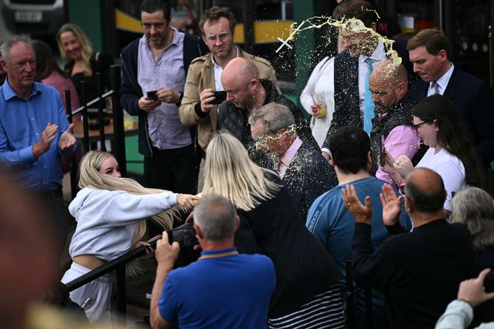 A woman flings her milkshake into Nigel Farage's face.