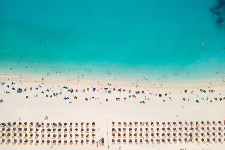 Famous beach Myrtos on amazing coast with beautiful beach with parasols on Ionian sea and lot of people. Kefalonia island, Greece