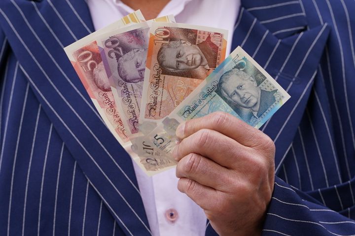 A person holds some of the newly released banknotes, featuring the king's portrait, outside the Bank of England, London on June 5. 