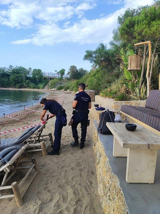 Αστυνομικοί απαγορεύουν την πρόσβαση στις ξαπλώστρες στην παραλία.