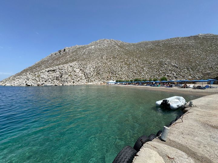 Άνθρωποι κάθονται στην παραλία του Αγίου Νικολάου από όπου πιστεύεται ότι ξεκίνησε ο Βρετανός γιατρός και παρουσιαστής της τηλεόρασης Μάικλ Μόσλεϊ, στο νησί Σύμη του νοτιοανατολικού Αιγαίου, Ελλάδα, Παρασκευή 7 Ιουνίου 2024. Σύμφωνα με την ελληνική αστυνομία, η μεγάλη επιχείρηση έρευνας και διάσωσης που βρίσκεται σε εξέλιξη στο μικρό νησί του ανατολικού Αιγαίου, τη Σύμη, δεν έχει ακόμη εντοπίσει τον Βρετανό γιατρό και τηλεοπτικό παρουσιαστή Μάικλ Μόσλεϊ, ο οποίος αγνοείται από το απόγευμα της Τετάρτης, αφού φέρεται να βγήκε για περίπατο (AP Photo/Antonis Mystiloglou).
