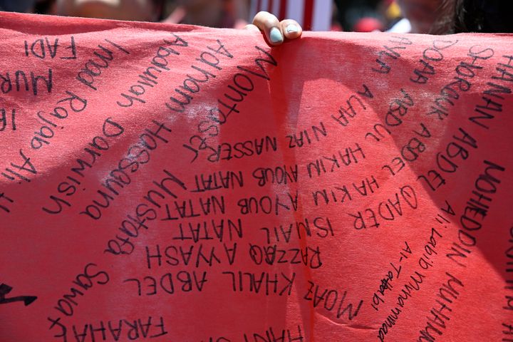 デモ参加者が掲げた赤い横断幕。イスラエル軍の攻撃で犠牲になったパレスチナ人らの名前が書かれていた