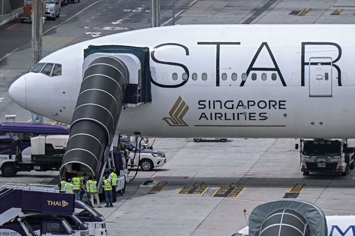 Officials enter the Singapore Airlines Boeing 777-300ER airplane after it made an emergency landing in Bangkok due to severe turbulence.