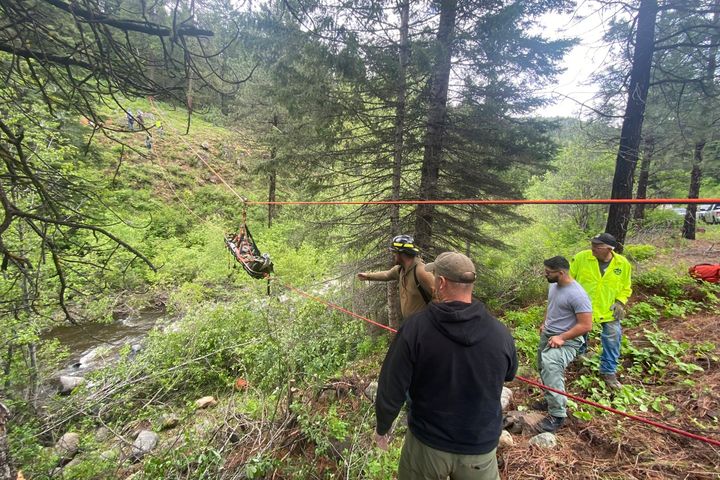 In this image provided by the Baker County Sheriff's Office, responders aid in rescue efforts after a vehicle went into an embankment on U.S. Forest Service Road 39 on June 3 in Oregon.