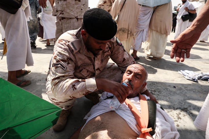 A man affected by the scorching heat is helped by a member of the Saudi Arabia security forces as Muslim pilgrims arrive to perform the symbolic "stoning of the devil" ritual as part of the Hajj pilgrimage in Mina, near the holy city of Mecca, on June 16, 2024.