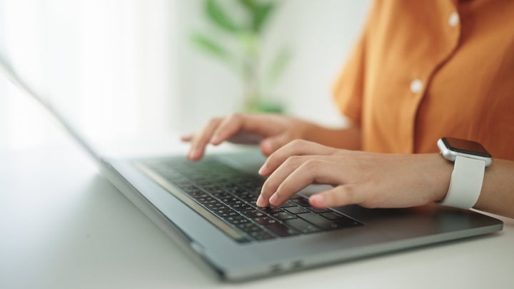 Asian teenage girl working on laptop at home.