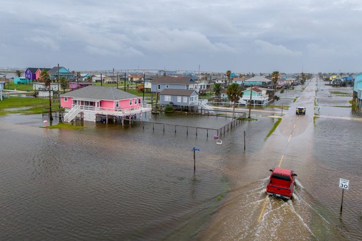 In an aerial view, vehicles drive through flooded neighborhoods on June 19, 2024, in Surfside Beach, Texas.