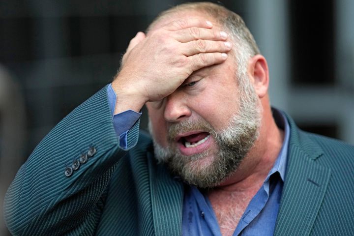 Right-wing conspiracy theorist Alex Jones wipes his forehead as he speaks to the media after arriving June 14 at a federal courthouse in Houston for a hearing in front of a bankruptcy judge.