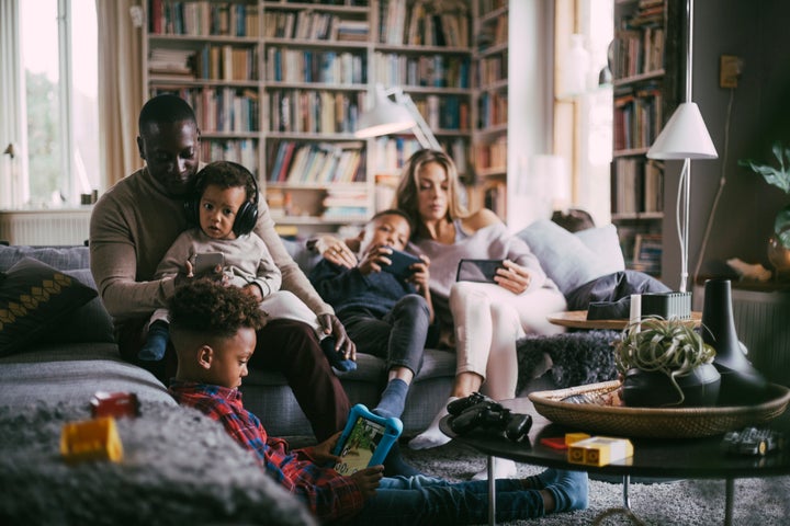 Eine Familie nutzt Geräte in ihrem Wohnzimmer