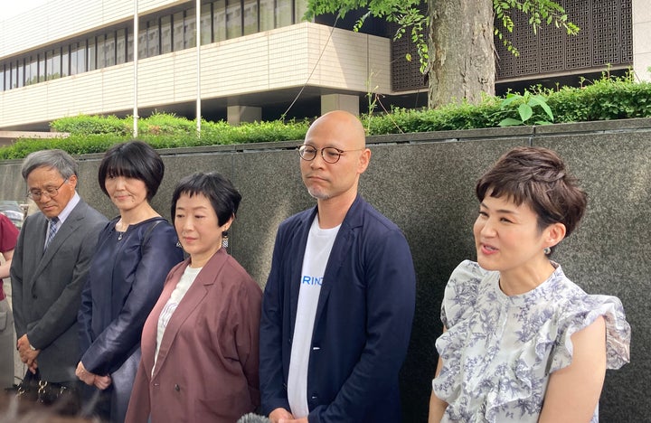 裁判所の前で記者団の質問に答える原告ら