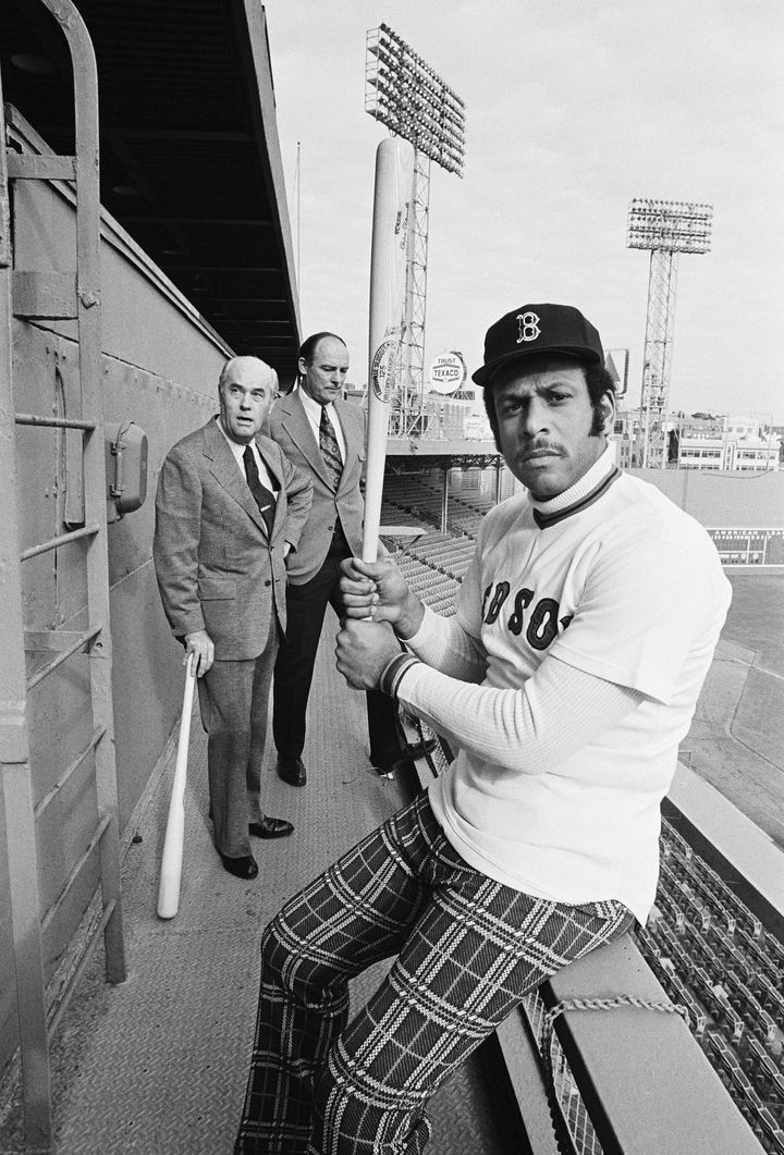 FILE- Orlando Cepeda, right, waves a bat for photographers after the Boston Red Sox announced they had signed Cepeda as their first design hitter, at Fenway Park in Boston.  General manager Dick OConnell, left, and Haywood Sullivan, vice president, player personnel, look on.  (AP photo/file)
