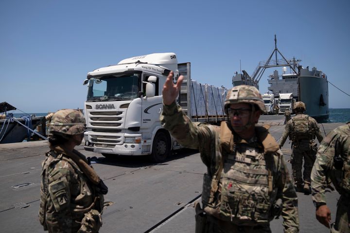 A U.S. Army soldier gestures as trucks loaded with humanitarian aid arrive at the U.S.-built floating pier before reaching the beach on the coast of the Gaza Strip, Tuesday, June 25, 2024.