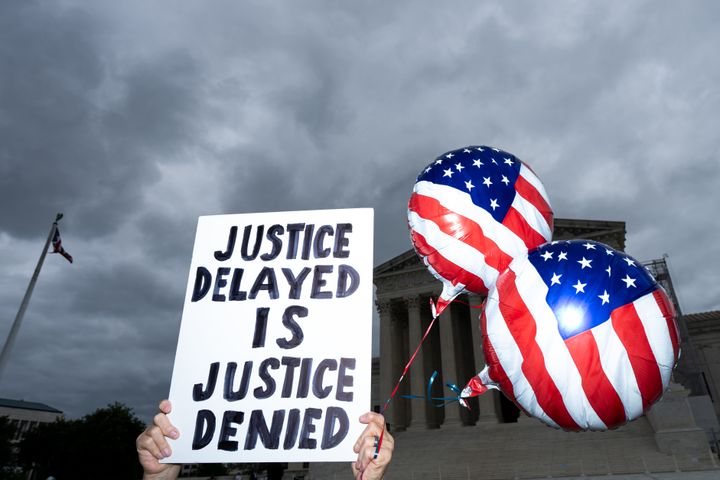ΟΥΑΣΙΓΚΤΟΝ - 1 ΙΟΥΛΙΟΥ: Ένας διαδηλωτής κρατάει μια πινακίδα και μπαλόνια με την αμερικανική σημαία μπροστά από το Ανώτατο Δικαστήριο περιμένοντας να ανακοινώσει το δικαστήριο την απόφασή του για την προεδρική ασυλία στην Ουάσιγκτον τη Δευτέρα, 1 Ιουλίου 2024. (Bill Clark/CQ-Roll Call, Inc μέσω Getty Images)