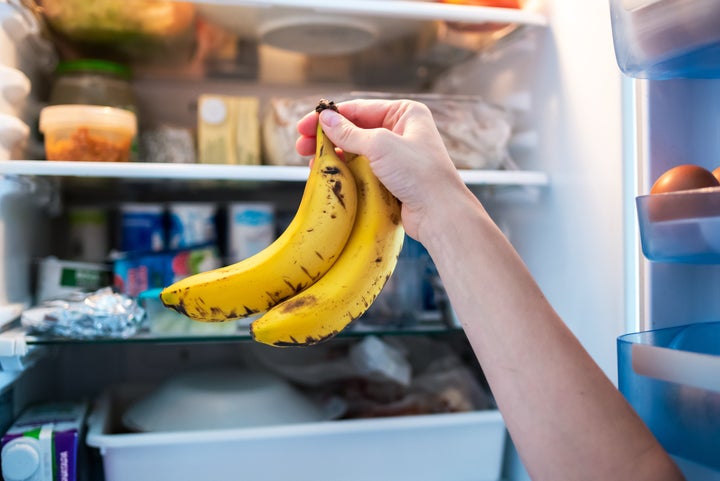 Woman's hand putting two bananas in the refrigerator