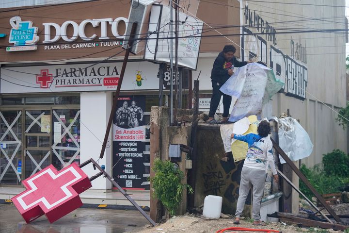 Bewohner reinigen den Eingang einer durch Hurrikan Beryl beschädigten Apotheke in Tulum, Mexiko, Freitag, 5. Juli 2024. (AP Photo/Fernando Llano)