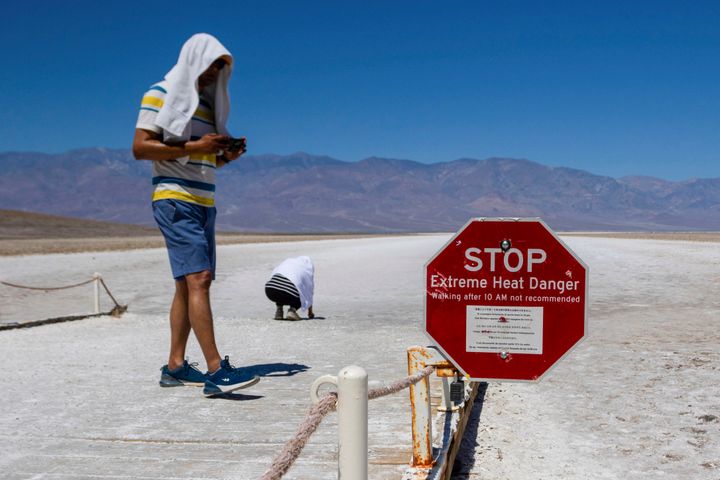 Two people cover themselves in white towels as they walk around Badwater Basin in Death Valley National Park, Calif., Sunday, July 7, 2024. Forecasters say a heat wave could break previous records across the U.S. (AP Photo/Ty ONeil)