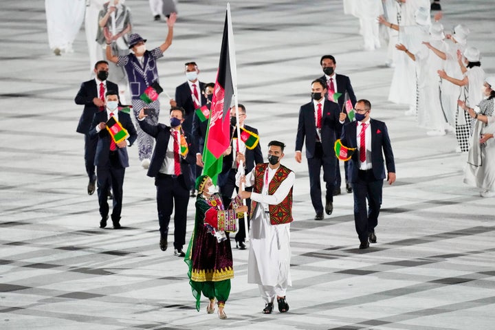 Kimia Yousofi, front left, and Farzad Mansouri, of Afghanistan, carry their country's flag during the opening ceremony of the Tokyo Olympics.