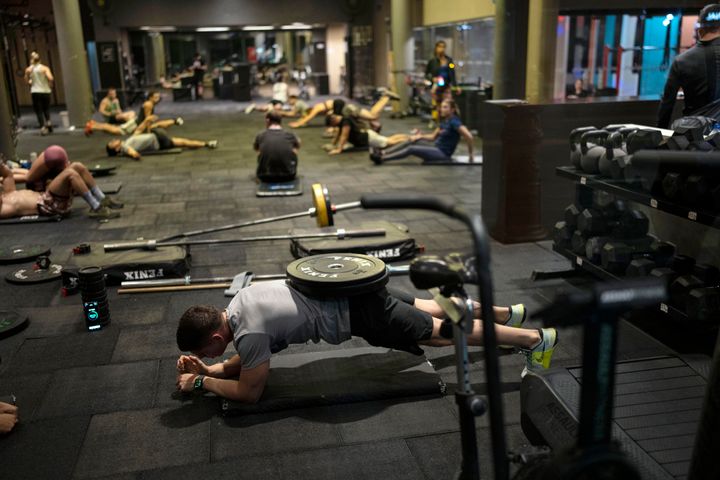 A man performs a plank while balancing a weight on his lumbar region, at a gym in downtown Buenos Aires, Argentina, Friday, June 7, 2024. (AP Photo/Rodrigo Abd)