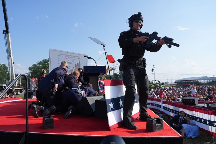 Secret Service agents cover former President Donald Trump during his campaign rally on July 13 in Butler, Pennsylvania. Trump ducked and was taken off stage after a gunman shot at him.