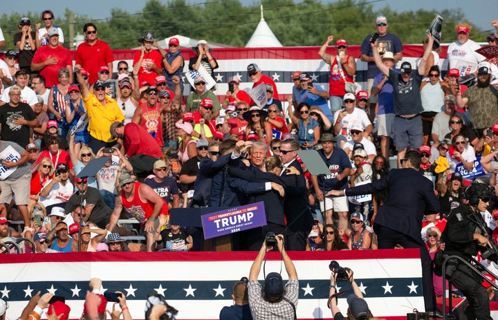 Trump is seen with blood on his face as Secret Service agents rush him off the stage.