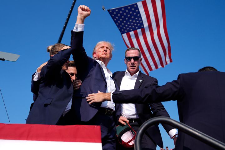 Trump gestures as he leaves the stage, surrounded by Secret Service agents.