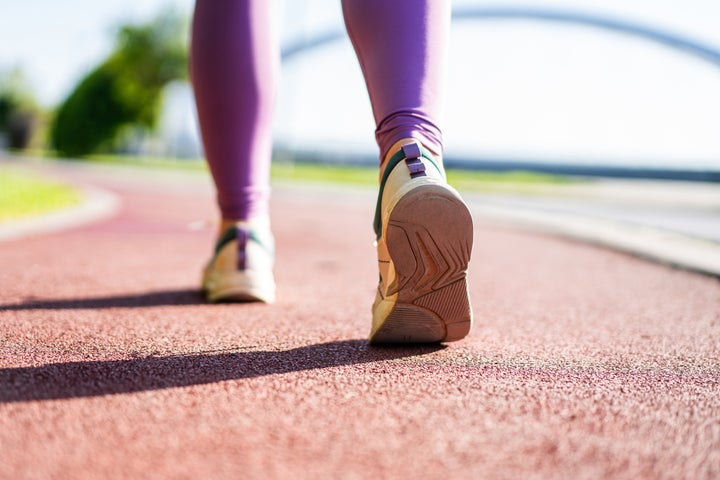 Close-up shot of shoe of female athlete running on a stadium track. Focus is on sneakers.