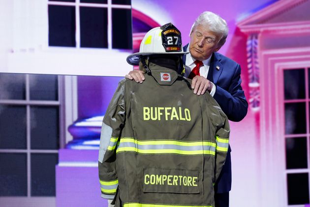 Republican presidential nominee and former President Donald Trump embraces the firefighter uniform of Corey Comperatore as he speaks on stage on the fourth day of the Republican National Convention at the Fiserv Forum on Thursday in Milwaukee.