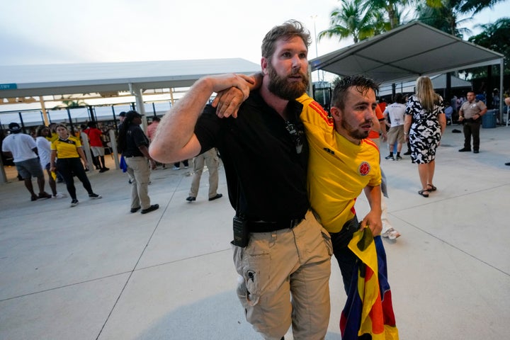 Ein Sicherheitsbeamter hilft einem Fan, der darauf wartet, das Stadion vor dem Copa-America-Finale zwischen Argentinien und Kolumbien in Miami Gardens, Florida, am Sonntag, 14. Juli 2024, zu betreten. (AP Photo/Lynne Sladky)