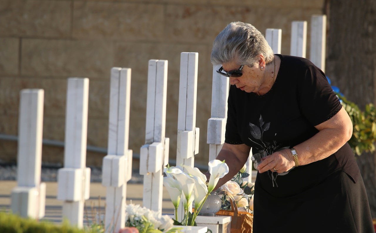 Συγγενής στρατιώτη που έχασε τη ζωή του το 1974 στα θλιβερά γεγονότα της Κύπρου ανάβει ένα κερί στη μνήμη του - Νεκροταφείο της Μακεδονίτισσας, 20 Ιουλίου 2024.