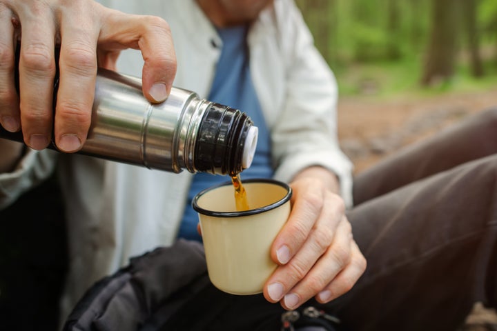 Senior man pouring tea from thermos to a metal mug