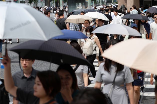 猛暑で日傘を差して交差点を歩く人たち＝2024年7月20日、東京・銀座