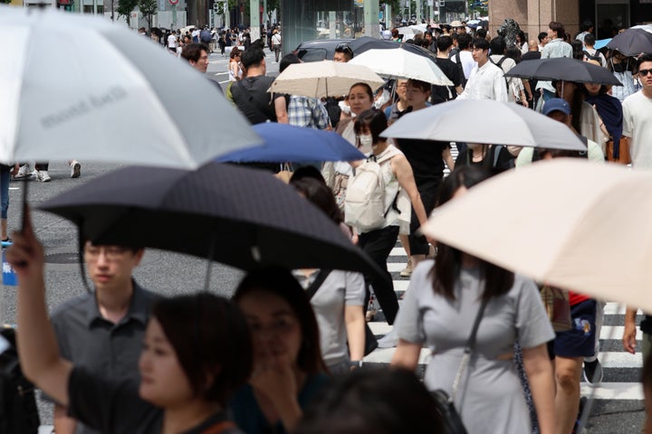 猛暑で日傘を差して交差点を歩く人たち＝2024年7月20日、東京・銀座